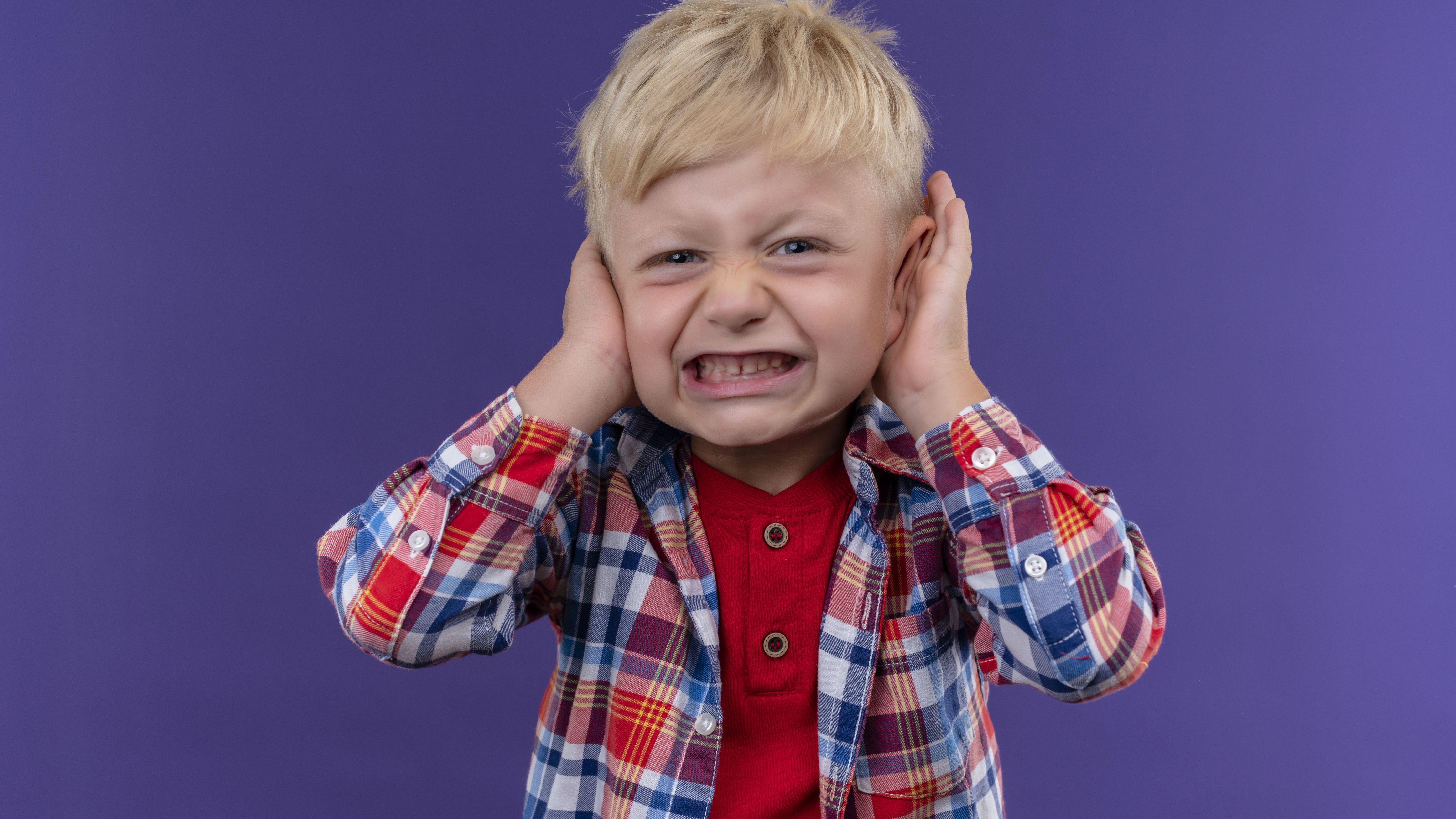 Angry Little Boy With Blonde Hair Wearing Checked Shirt Keeping Hands Ears